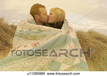 Couple kissing under blanket on beach View Large Photo Image Stock Photo - Couple kissing under blanket on beach. Fotosearch