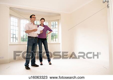 Stock Image - Couple look at room in vacant house. Fotosearch