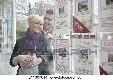 Picture - Couple looking into estate agents window. Fotosearch