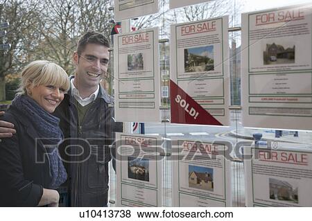 Couple looking into estate agents window View Large Photo Image Stock Photo - Couple looking into estate agents window. Fotosearch