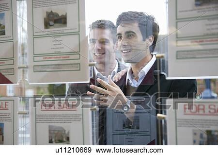 Couple looking into estate agents window View Large Photo Image Stock Photo - Couple looking into estate agents window. Fotosearch