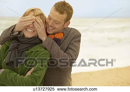 Couple on beach his hands over her eyes View Large Photo Image Stock Photography - Couple on beach his hands over her eyes. Fotosearch