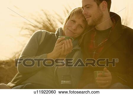 Couple outdoors cuddling with coffee View Large Photo Image Stock Image - Couple outdoors cuddling with coffee. Fotosearch