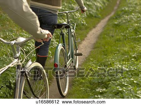 Stock Image - Couple pushing old bicycles, close-up. Fotosearch