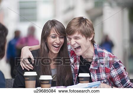 Couple seated at cafe table, laughing View Large Photo Image Picture - Couple seated at cafe table, laughing. Fotosearch