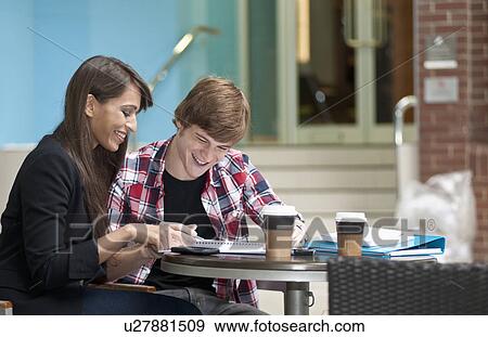 Couple seated at cafe table sharing note View Large Photo Image Stock Photo - Couple seated at cafe table sharing note. Fotosearch