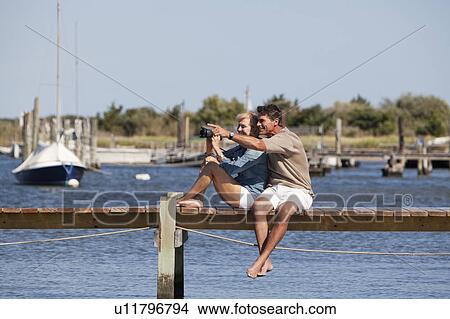 Picture - Couple sitting on a dock. Fotosearch