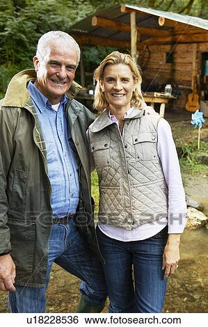 Couple standing outside cabin View Large Photo Image Stock Photograph - Couple standing outside cabin. Fotosearch
