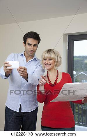 Couple taking photo in new apartment View Large Photo Image Stock Photo - Couple taking photo in new apartment. Fotosearch
