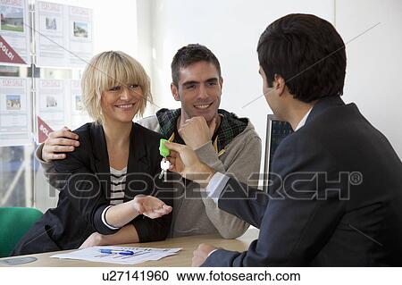 Stock Image - Couple visiting estate agents office. Fotosearch