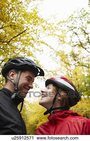 Stock Image - Couple with cycle helmets on having fun. Fotosearch