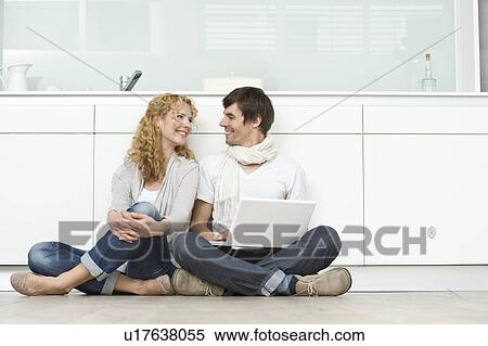 Stock Photography - Couple with laptop on kitchen floor. Fotosearch