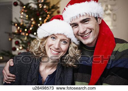 Couple with Santa hats in front of tree View Large Photo Image Stock Image - Couple with Santa hats in front of tree. Fotosearch
