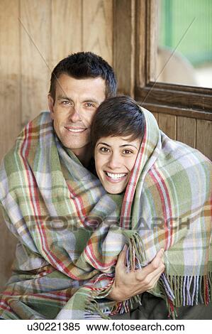 Stock Photography - Couple wrapped in a blanket in a huy. Fotosearch