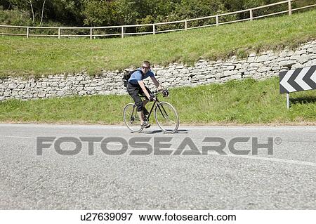 Stock Photo - Cyclist coming around a long bend. Fotosearch