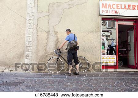 Stock Photo - Cyclist taking a break in village. Fotosearch