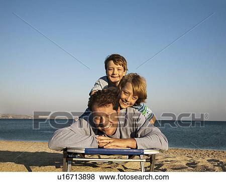 Stock Photo - Dad and two boys on sunlounger. Fotosearch