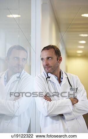 Stock Image - Doctor against a window, waiting. Fotosearch