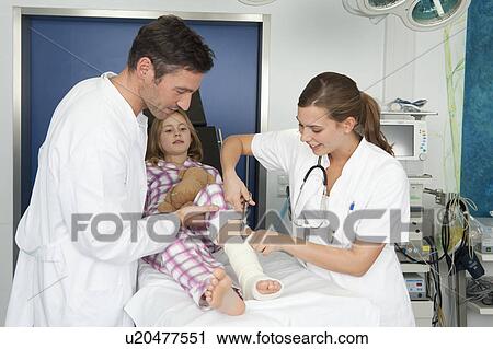 Stock Image - Doctor and nurse cut opening plaster. Fotosearch