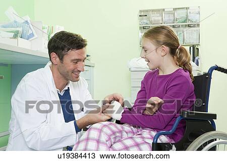 Stock Image - Doctor examining girls hand. Fotosearch