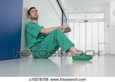 Doctor in scrubs, resting on the floor View Large Photo Image Stock Photo - Doctor in scrubs, resting on the floor. Fotosearch