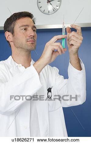 Stock Image - Doctor inspecting injection. Fotosearch