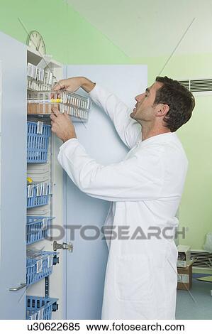 Stock Photography - Doctor looking for medication in locker. Fotosearch