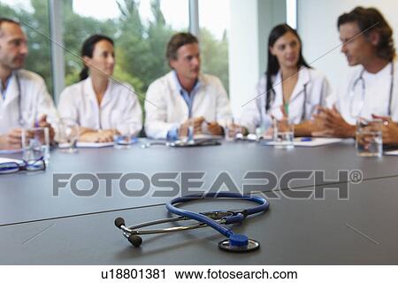 Stock Image - Doctors meeting, stethoscope on table. Fotosearch