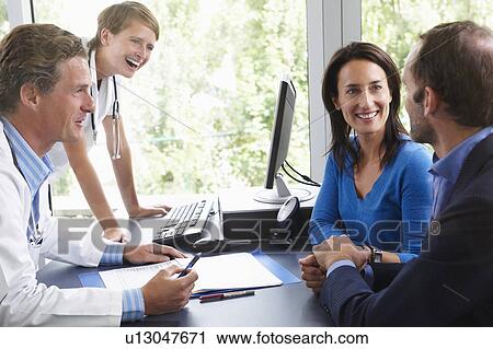 Stock Image - Doctors with patients, in office. Fotosearch