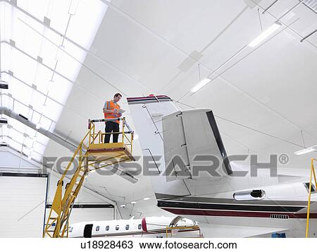 Stock Image - Engineer inspects jet aircraft. Fotosearch