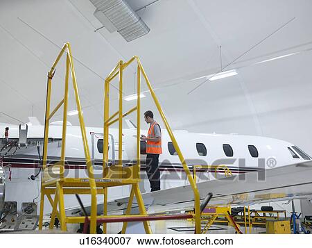 Engineer inspects jet aircraft View Large Photo Image Stock Photo - Engineer inspects jet aircraft. Fotosearch
