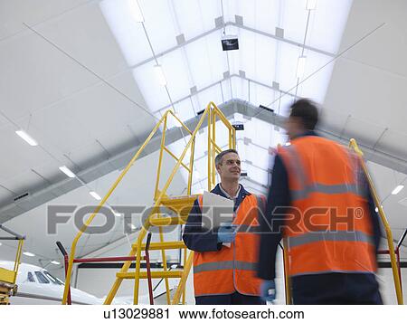 Engineers in aircraft hangar View Large Photo Image Stock Image - Engineers in aircraft hangar. Fotosearch