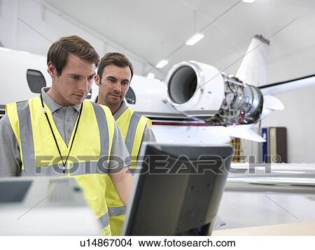 Picture - Engineers in aircraft hangar with jet. Fotosearch