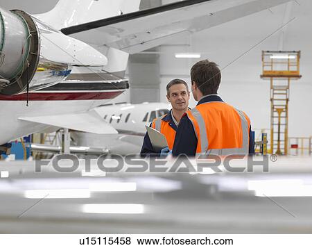 Stock Photo - Engineers in aircraft hangar with jets. Fotosearch