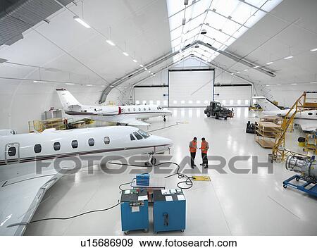 Stock Photo - Engineers in jet aircraft hangar. Fotosearch