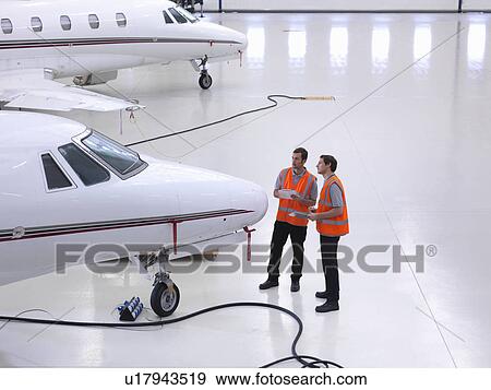 Engineers in jet aircraft hangar View Large Photo Image Stock Photo - Engineers in jet aircraft hangar. Fotosearch