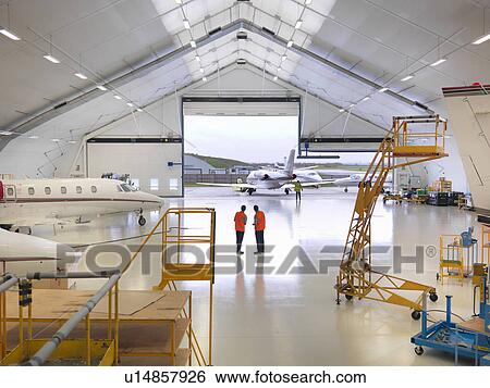 Engineers in jet aircraft hangar View Large Photo Image Stock Photograph - Engineers in jet aircraft hangar. Fotosearch