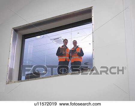 Stock Photo - Engineers look out of window in hangar. Fotosearch