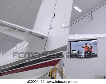 Stock Image - Engineers look out onto jet aircraft. Fotosearch