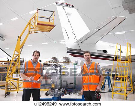 Stock Photo - Engineers with jet engine in hangar. Fotosearch