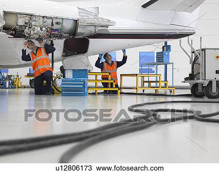 Stock Image - Engineers work on jet aircraft. Fotosearch