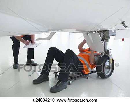 Stock Image - Engineers working on jet aircraft. Fotosearch