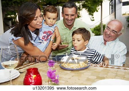 Family blowing candles out on cake View Large Photo Image Stock Photography - Family blowing candles out on cake. Fotosearch