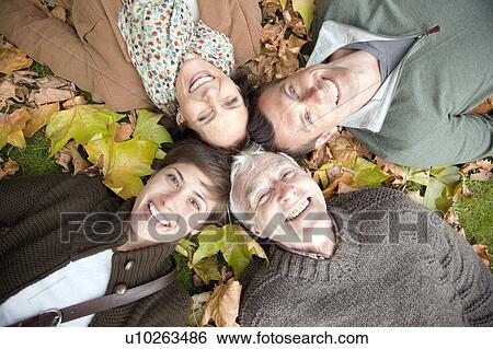 Stock Photograph - Family lying in autumn leaves in a park. Fotosearch