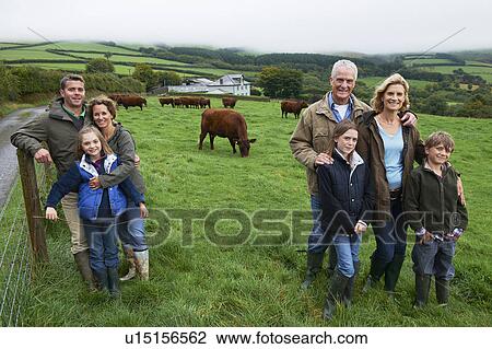 Stock Image - Family on farm in a field with cows. Fotosearch