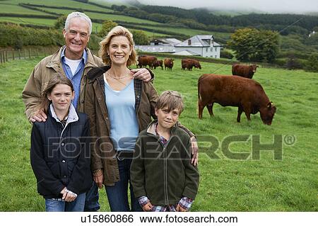 Stock Photograph - Family on farm in a field with cows. Fotosearch