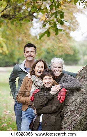 Stock Photograph - Family portrait by tree in the park. Fotosearch