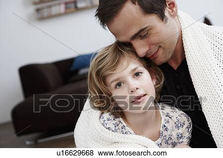 Stock Photo - Father and daughter cuddling under coat. Fotosearch