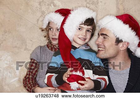 Father and Kids wearing Santa hats View Large Photo Image Stock Photo - Father and Kids wearing Santa hats. Fotosearch