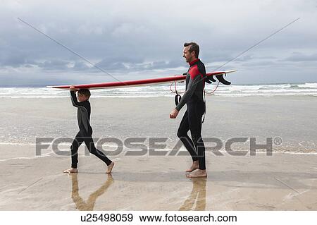 Stock Photo - Father and Son carrying surf board. Fotosearch